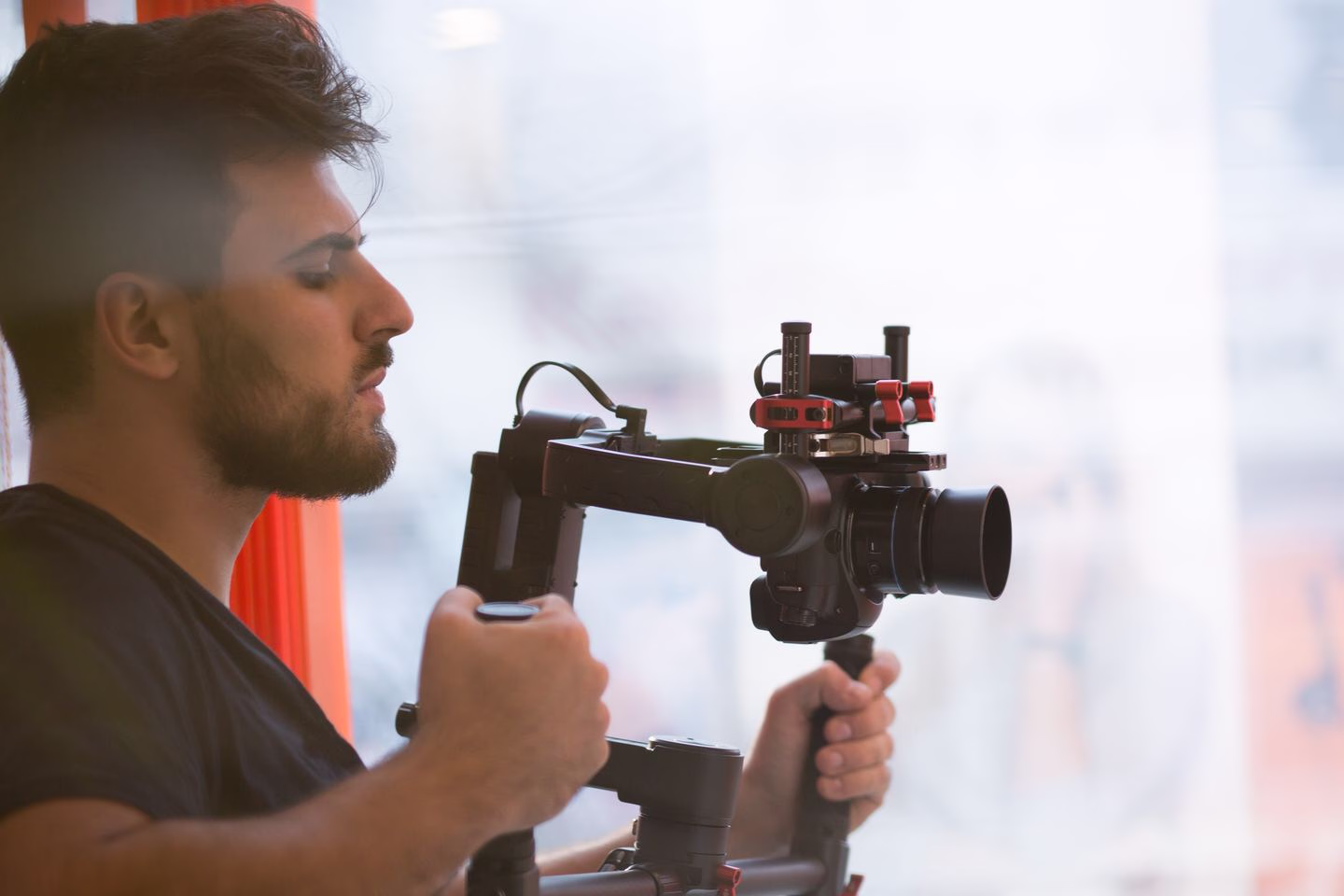 Videographer filming beside a window — Source Select.