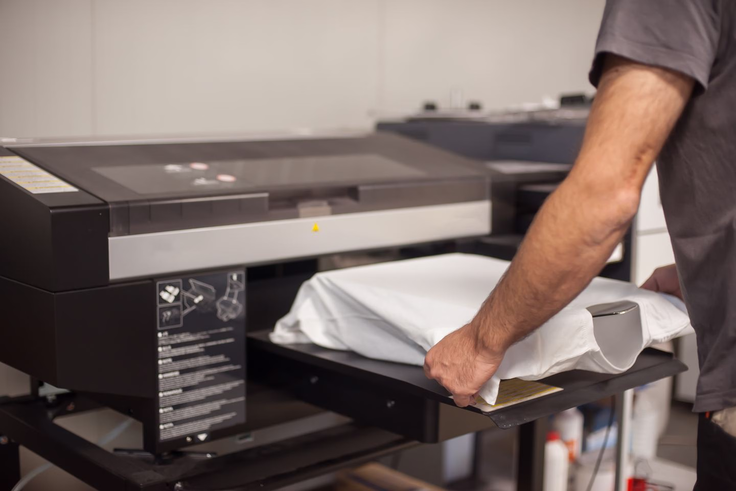 Operator loading a shirt into a direct-to-garment printer — Source Select.
