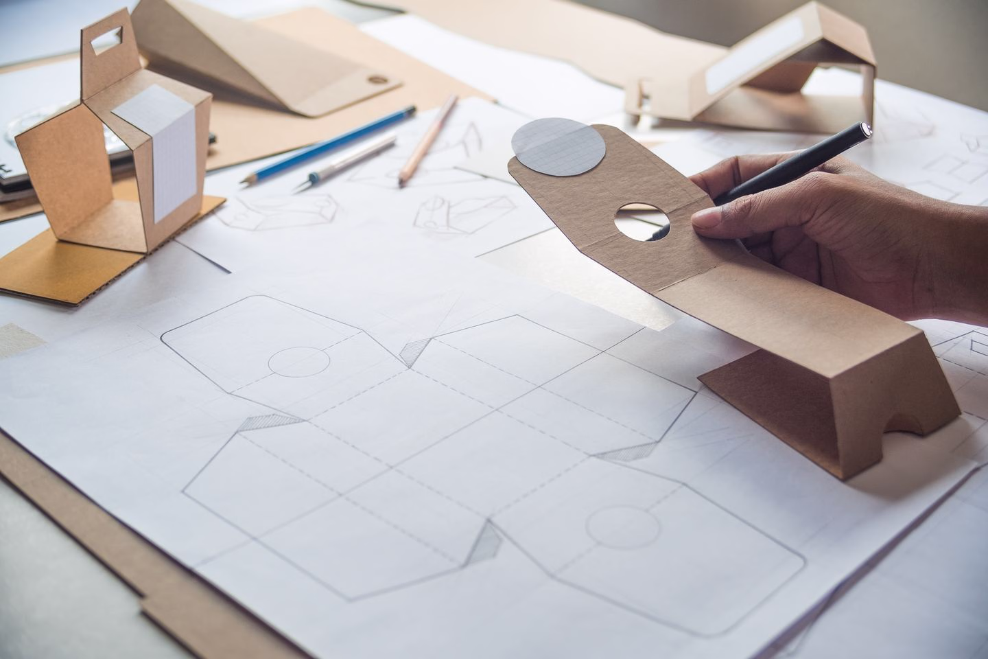 Hands assembling a cardboard packaging prototype — Source Select.