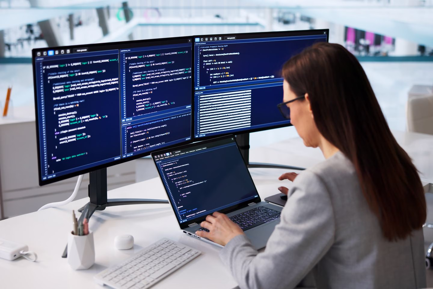 Developer working at code screens in a bright office — Source Select.