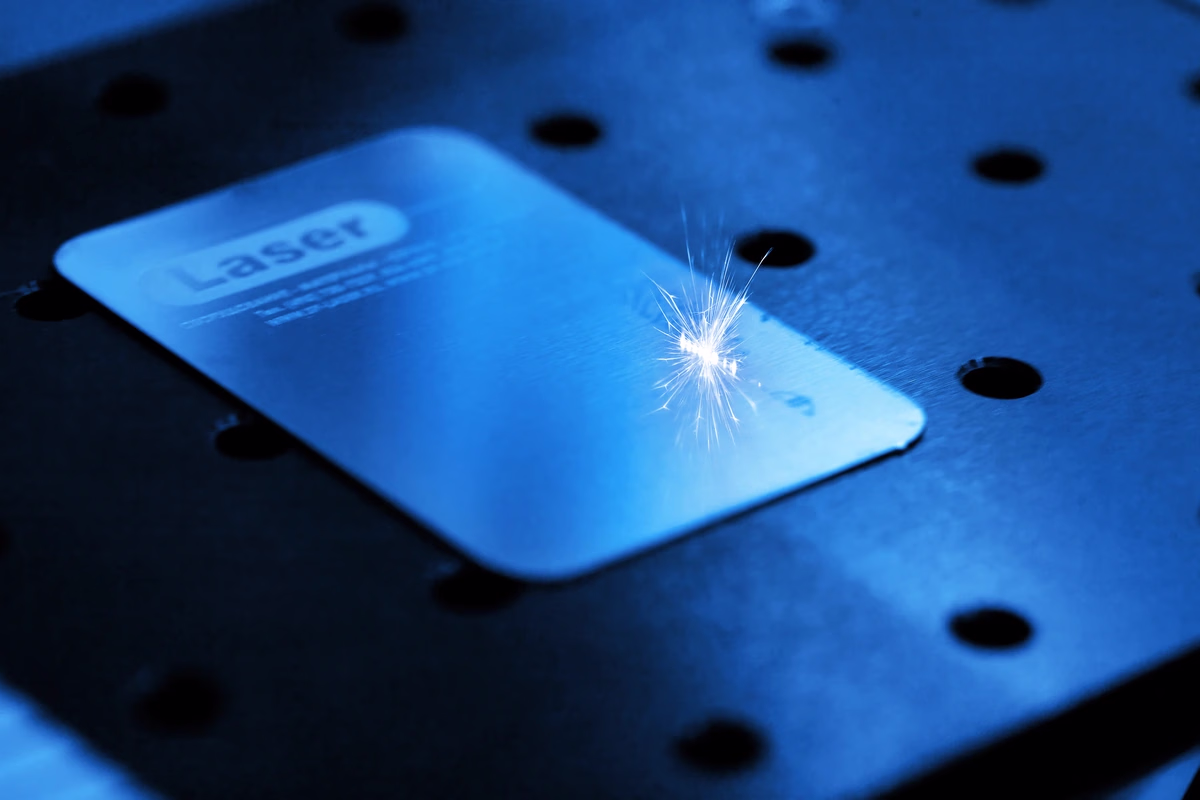 Laser engraving a metal plate under blue light — Source Select.