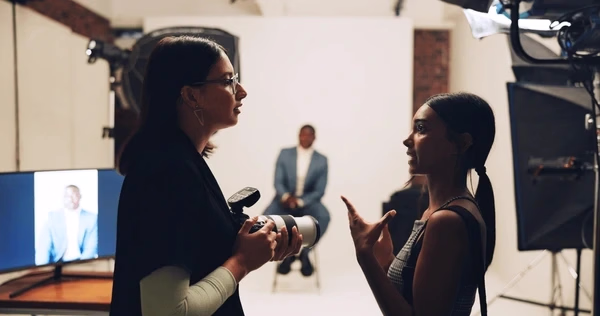 Photographer and colleague preparing a portrait shoot — Source Select.